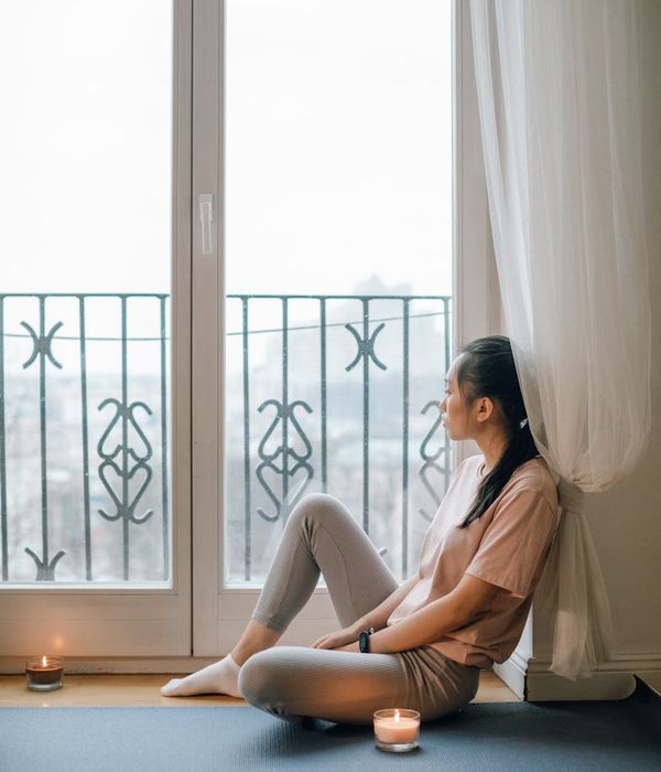 Person sitting comfortably on a yoga mat with candles.